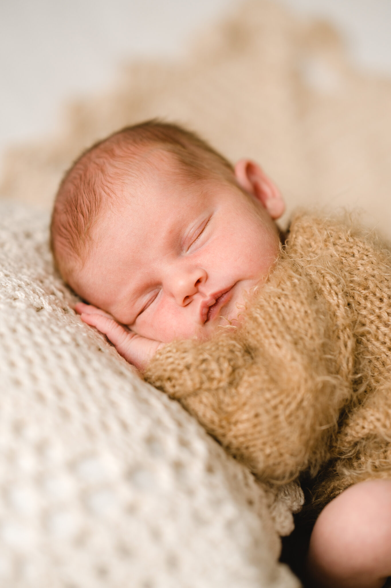 baby in neutral fluffy grow asleep with head on crochet pillow