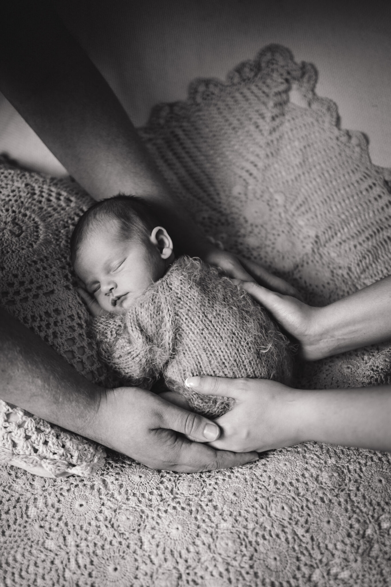 mum and dads hands holding newborn baby black and white image